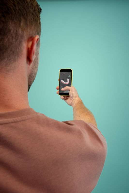 Man som kontrollerar förloppet av sin DR SMILE-behandling via DR SMILE-appen på sin telefon