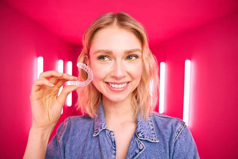 [CRO] Blond - Woman - Aligner in hand - Looking at the right - Pink - Light - Background - Desktop